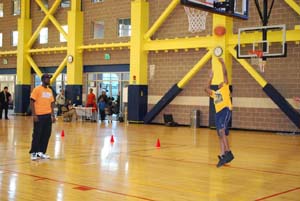 Salvation Army Kroc Center Fitness and Recreation Attendant Kenneth Heyward overseeing 10-year-old Jordan Edge of Dorchester as he participates in the Dribble, Dish & Swish basketball skills competition.